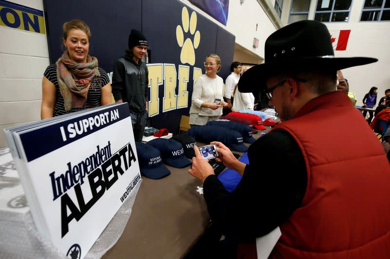 FILE PHOTO: A man in a cowboy hat takes a photo while attending a rally for Wexit Alberta, a separatist group seeking federal political party status, in Calgary