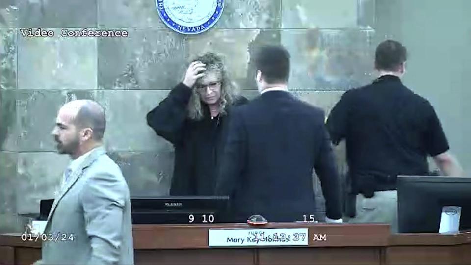 In this image from video provided by the Clark County District Court, Judge Mary Kay Holthus is seen cradling her head after a defendant launched over her desk during his sentencing in a felony battery case, Wednesday, Jan. 3, 2024 in Las Vegas. Authorities say the judge suffered minor injuries n the attack while a courtroom marshal suffered a bleeding gash on his forehead and a dislocated shoulder. | Clark County District Court via Associated Press
