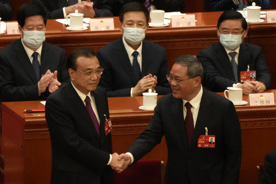 Newly elected Chinese Premier Li Qiang at right shakes hands with former Premier Li Keqiang during a session of China's National People's Congress (NPC) at the Great Hall of the People in Beijing, Saturday, March 11, 2023. (AP Photo/Mark Schiefelbein)