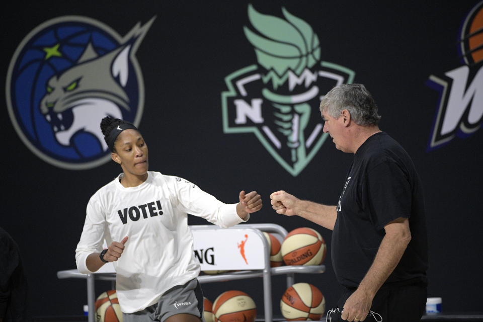 A'ja Wilson in a white &quot;VOTE!&quot; T-shirts giving a fist bump to Bill Laimbeer. 