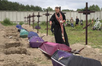 A priest prays for unidentified civilians killed by Russian troops during Russian occupation in Bucha, on the outskirts of Kyiv, Ukraine, Thursday, Aug. 11, 2022. Eleven unidentified bodies exhumed from a mass grave were buried in Bucha Thursday (AP Photo/Efrem Lukatsky)