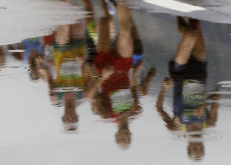 Teilnehmer des Olympischen Marathonlaufs der Männer spiegeln sich in einer Pfütze. Während des Wettkampfs, der die Läufer unter anderem entlang der Bucht von Guanabara führte, regnete es die meiste Zeit. (Bild: Luca Bruno/AP)