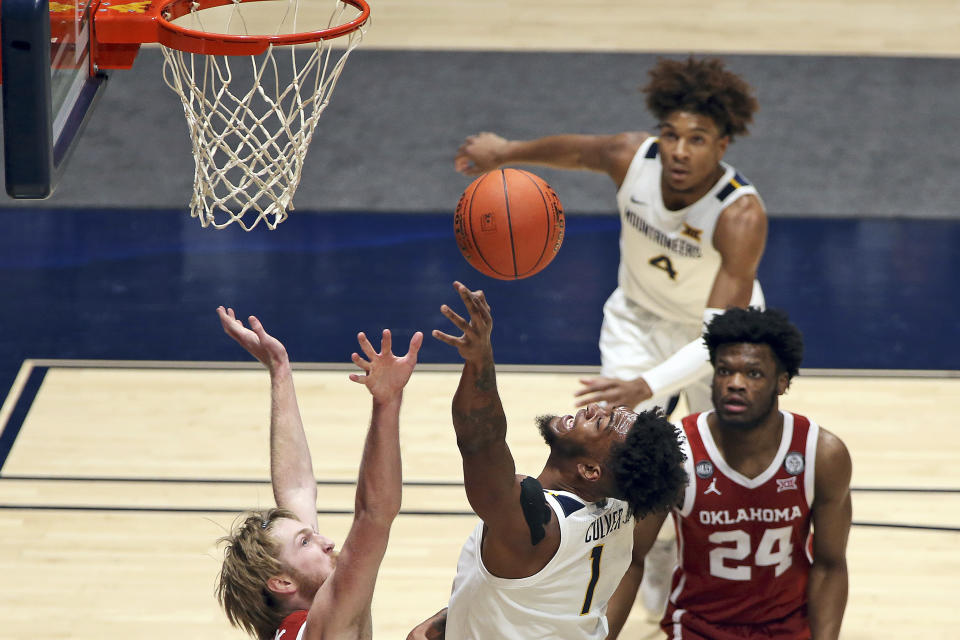 West Virginia forward Derek Culver (1) shoots as Oklahoma forward Brady Manek (35) and guard Elijah Harkless (24) defends during the first half of an NCAA college basketball game Saturday, Feb. 13, 2021, in Morgantown, W.Va. (AP Photo/Kathleen Batten)