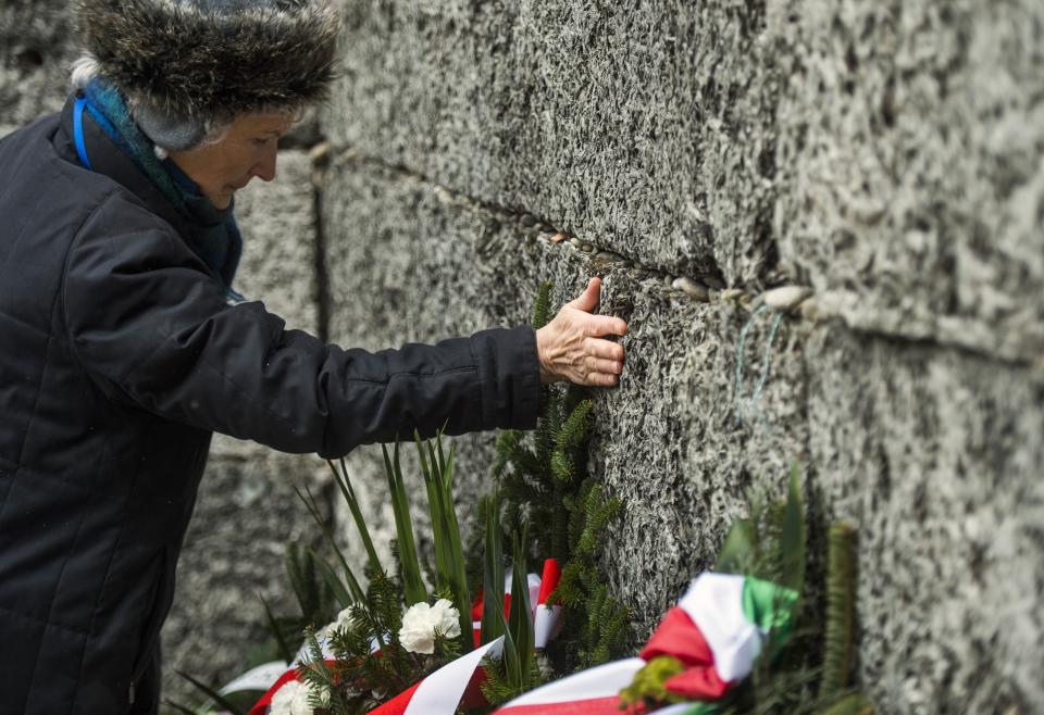 A Holocaust survivor pays tribute to fallen comrades putting her hand on the 'death wall' execution spot in the former Auschwitz concentration camp in Oswiecim, Poland, on the 70th anniversary of the liberation of the Nazi death camp on January 27, 2015. Seventy years after the liberation of Auschwitz, ageing survivors and dignitaries gather at the site synonymous with the Holocaust to honour victims and sound the alarm over a fresh wave of anti-Semitism.