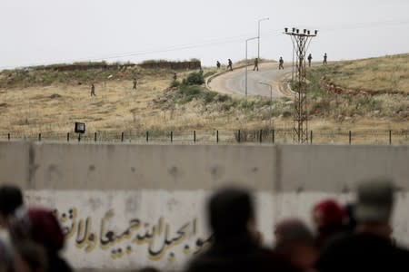 Turkish soldiers walk at the Atmeh crossing on the Syrian-Turkish border, as seen from the Syrian side, in Idlib governorate