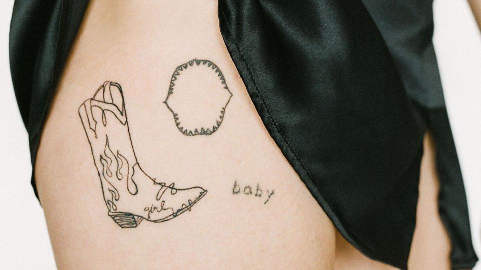 woman revealing delicate hip tattos