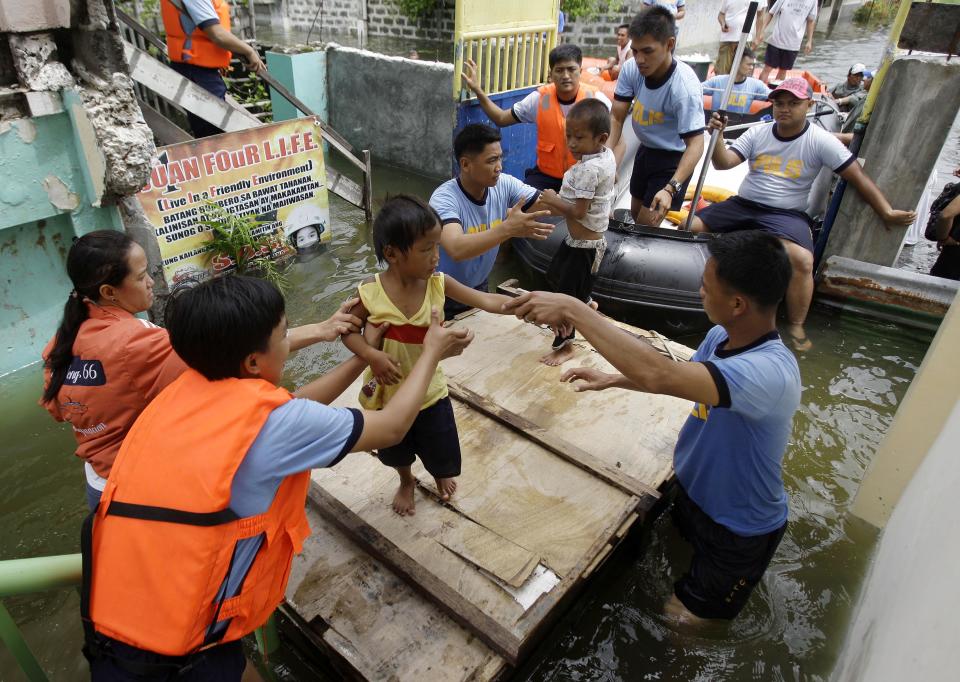 Rescuers move children to an evacuation center at Malabon city, north of Manila, Philippines on Wednesday, Aug. 1, 2012. Fierce winds and heavy rains from the slow-moving Typhoon Saola battered the country, displacing 154,000 people. (AP Photo/Aaron Favila)