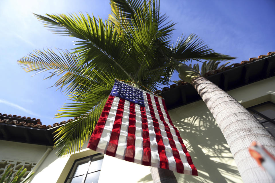 FILE - This March 7, 2017 file photo shows a U.S. flag hanging from a palm tree outside a polling place at the Bel-Air Bay Club in the Pacific Palisades area of Los Angeles. With the 2020 elections approaching, the latest California voter registration figures tell a familiar story: Democrats are expanding their ranks, Republicans are struggling and the fastest-growing group remains those voters aligned with no party at all - independents. The figures released Wednesday, Nov. 6, 2019 by Secretary of State Alex Padilla also show that more than 80 percent of eligible residents are registered to vote, the highest percentage since 1952. (AP Photo/Reed Saxon, File)