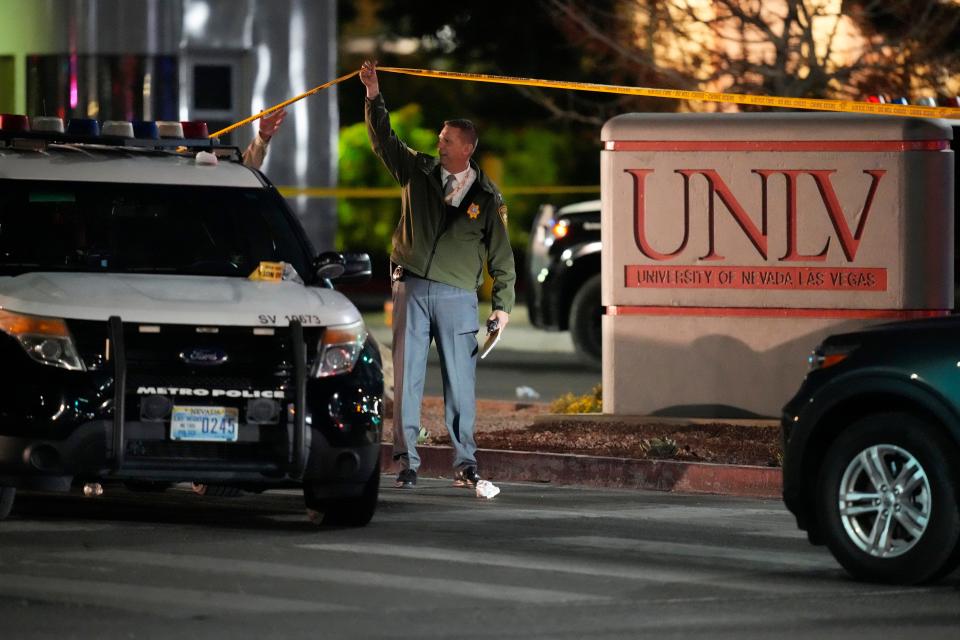 A police officer walks under crime scene tape in the aftermath of a shooting at the University of Nevada, Las Vegas, Wednesday, Dec. 6, 2023, in Las Vegas.