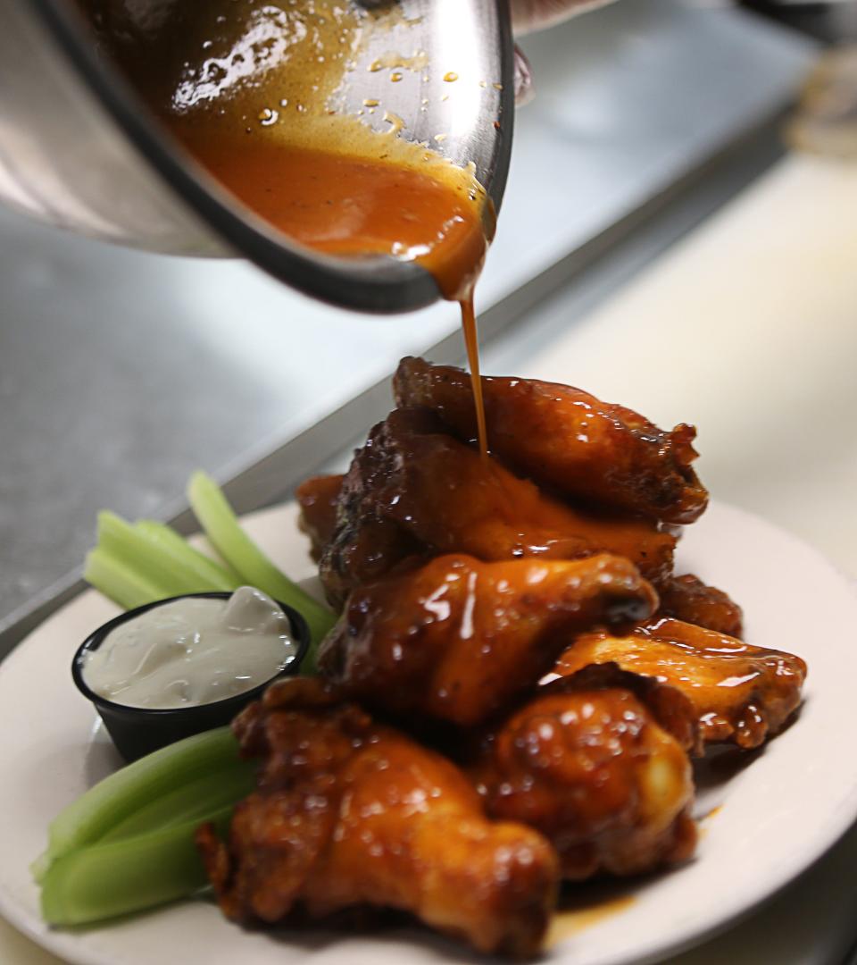 Sauce gets poured on the chicken wings made by 2 Fat Guys American Grill in Hockessin.