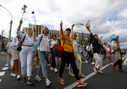 Belarusian women carry flowers on a rally in solidarity with protesters injured in the latest rallies against the results of the country's presidential election in Minsk, Belarus, Thursday, Aug. 13, 2020. Hundreds of people were back on the streets of Belarus' capital on Thursday morning, forming long "lines of solidarity" in protest against an election they say was rigged to extend the rule of the country's authoritarian leader and against a crackdown on rallies that followed the vote. (AP Photo/Sergei Grits)