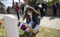 British expatriate Steven Oldrid, left, directs people where to lay wooden crosses with names of WWII dead and flowers during D-Day ceremonies at the local war cemetery in Benouville, Normandy, France on Saturday, June 6, 2020. Due to coronavirus measures many relatives and veterans will not make this years 76th anniversary of D-Day. Oldrid will be bringing it to them virtually as he places wreaths and crosses for families and posts the moments on his facebook page. (AP Photo/Virginia Mayo)