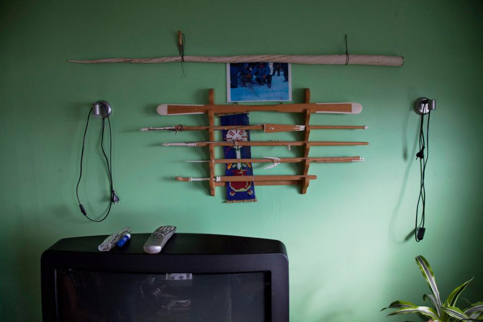 A narwhal whale tusk from a hunt along with miniature replicas of traditional kayaking and hunting tools adorning a wall above a television set inside the home of an Inuit family in Qeqertarsuaq, Disko Island, Greenland.