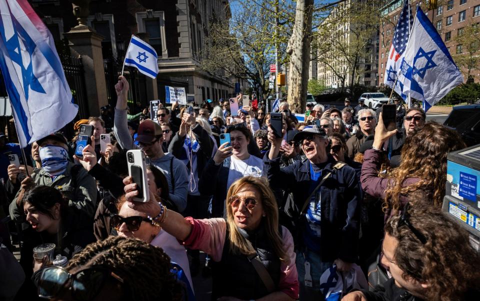 A crowd hold Israeli flags and appear to be chanting in a New York street