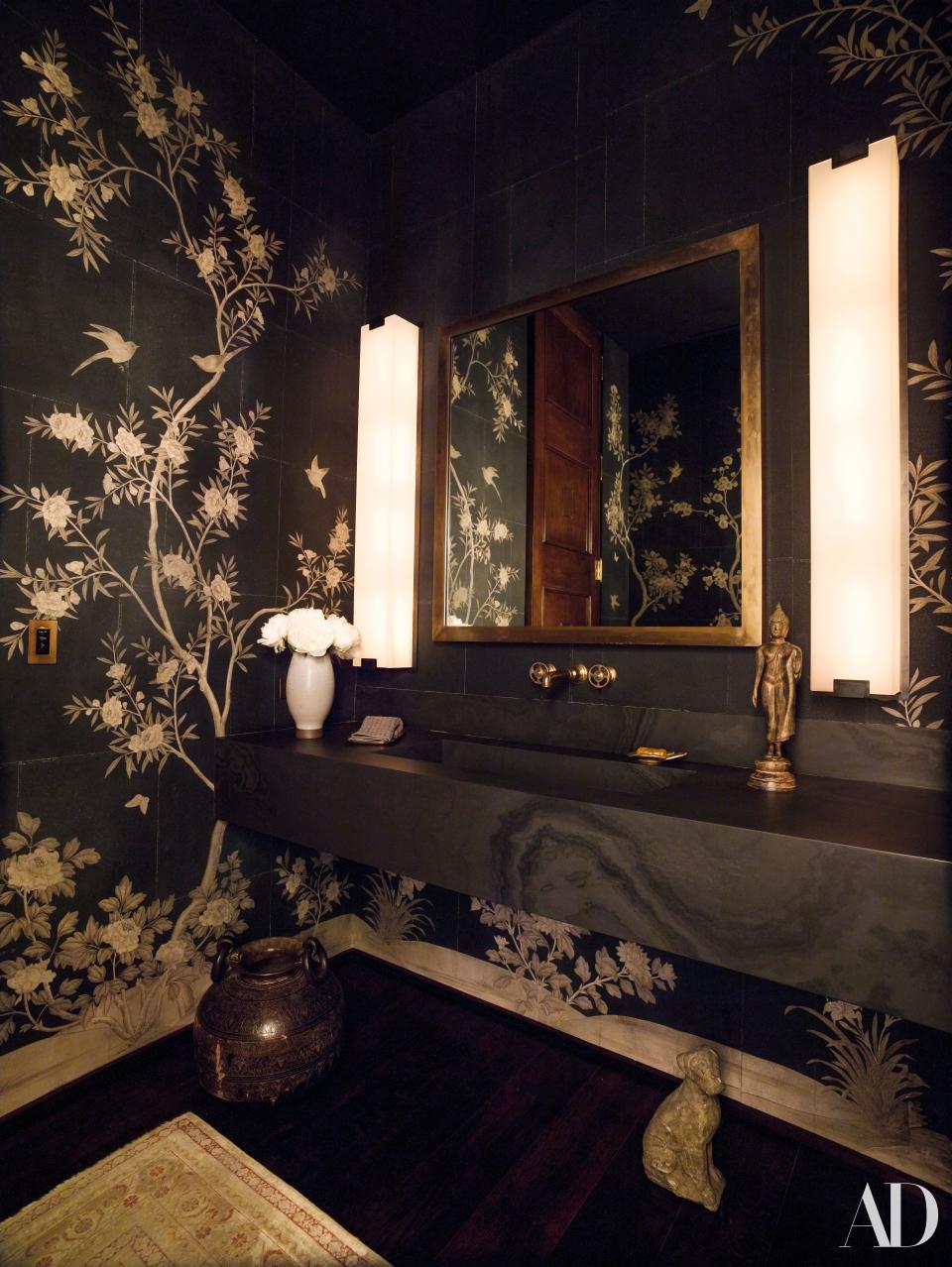 A powder room is clad in hand-painted wallpaper.