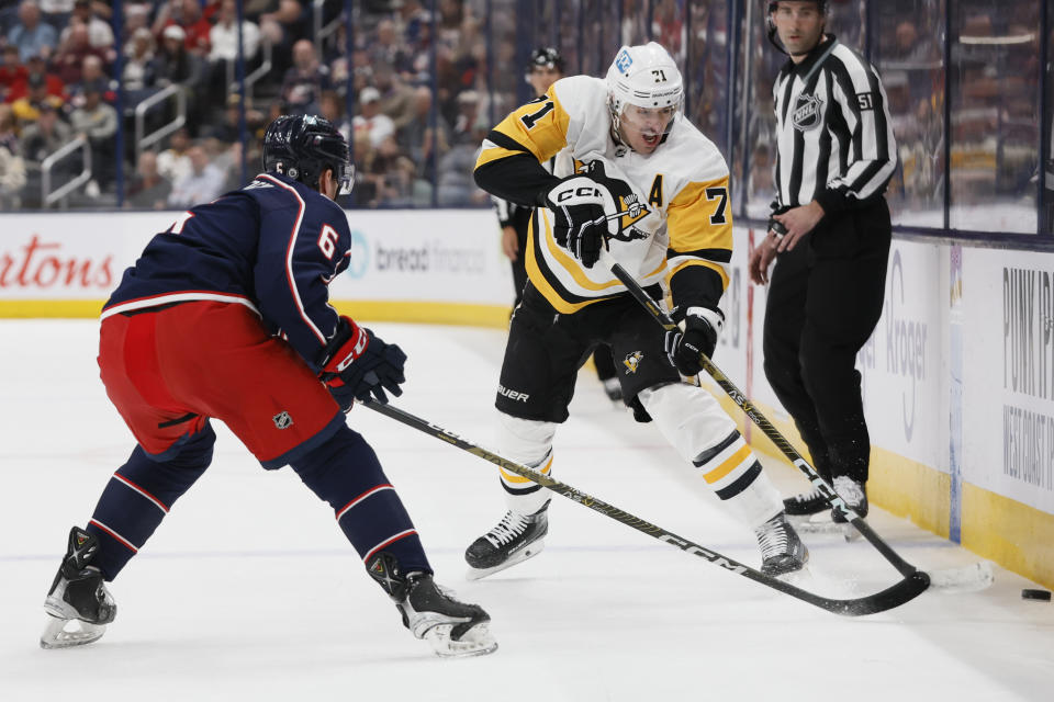 Pittsburgh Penguins' Evgeni Malkin, right, dumps the puck as Columbus Blue Jackets' Billy Sweezey defends during the first period of an NHL hockey game Thursday, April 13, 2023, in Columbus, Ohio. (AP Photo/Jay LaPrete)