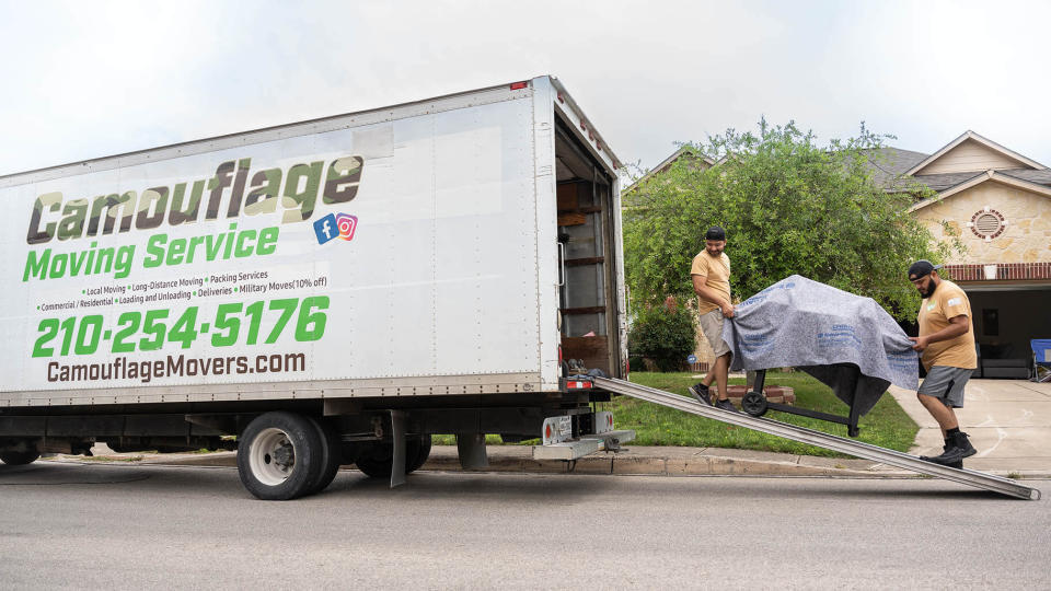 Two Camouflage Moving Service workers load a company truck.