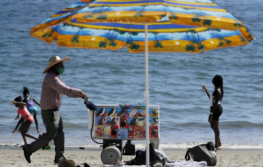 LONG BEACH, CA - JULY 32, 2020. An ice cream vendors pushes a cart along the sand at Junipero Beach in Long Beach on a warm Friday afternoon, July 31, 2020. A heat wave is expected to grip Southern California through the weekend, with inland temperatures reaching triple digits. (Luis Sinco/Los Aneles Time)