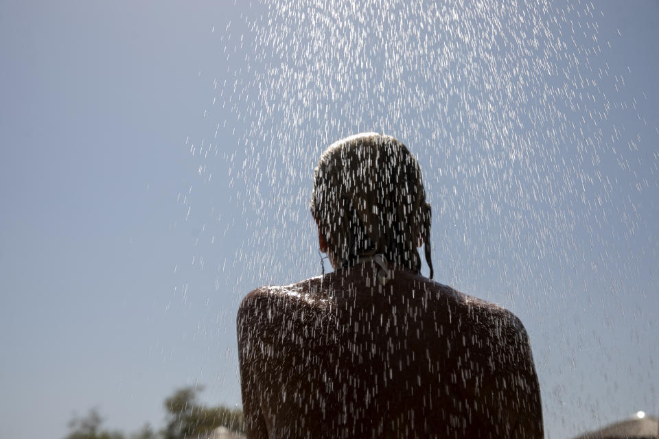 A woman takes a shower at a beach of Lagonissi village, a few miles southwest of Athens, on Thursday, July 29, 2021. One of the most severe heat waves recorded since 1980s scorched southeast Europe on Thursday, sending residents flocking to the coast, public fountains and air-conditioned locations to find some relief, with temperatures rose above 40 C (104 F) in parts of Greece and across much of the region. (AP Photo/Yorgos Karahalis)