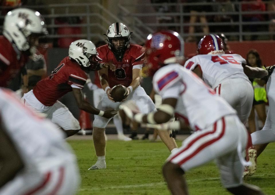 West Florida quarterback John Nicholas (No. 9) hands off to Marquez Jones (No. 4) as the Pine Forest defense closes in during Friday night's game against the Eagles.