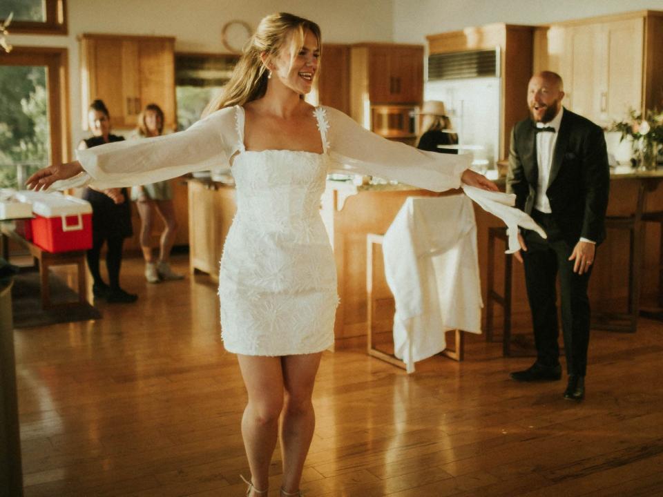 A bride twirls in her wedding dress as her groom looks on.