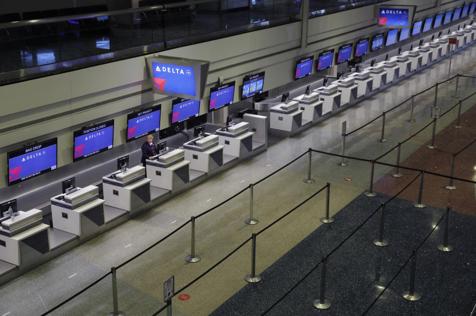 In this April 21, 2020, photo, a lone person works at the Delta airlines check-in desk at McCarran International airport in Las Vegas. Nevada's governor shuttered the glitzy casinos and nightlife attractions of Las Vegas in mid-March, leaving much of the famous gambling mecca empty. (AP Photo/John Locher)