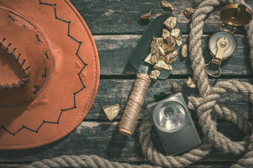 Gold nuggets on a trowel beside exploring tools.