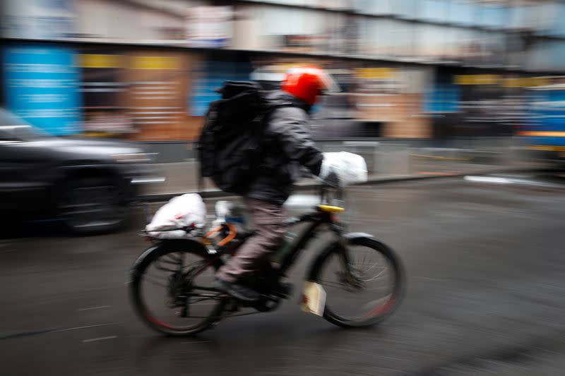 Delivery rider on nearly deserted Fulton street in lower Manhattan during outbreak of coronavirus disease (COVID-19) in New York