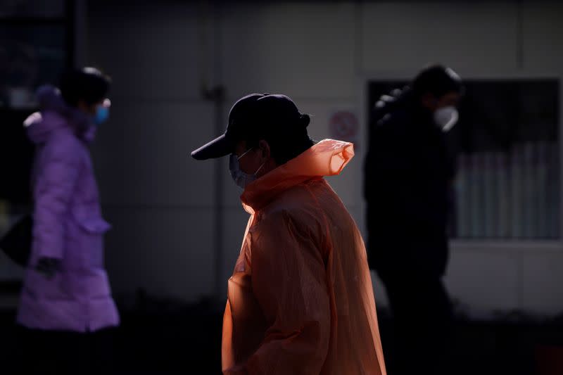 Pedestrian wearing raincoat and face mask is seen on a street, as the country is hit by an outbreak of the novel coronavirus, in Shanghai