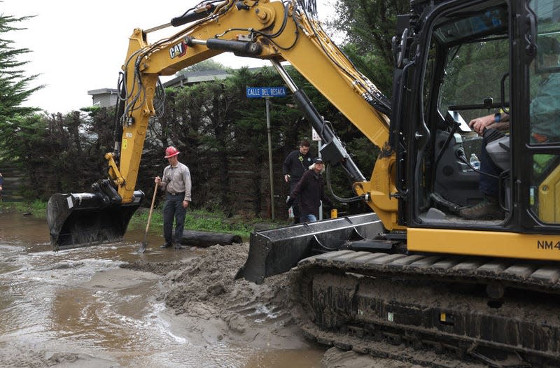 A Marin County firefighter looks on as a backhoe removes sand from a street after large waves flooded a neighborhood on January 05, 2023 in Stinson Beach, California.