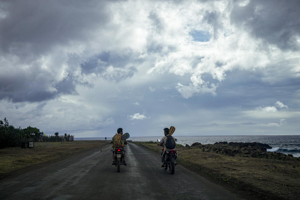 Konturi Atán, un historiador rapanui de 36 años, a la derecha, conduce su motocicleta a una sesión de entrenamiento para el desafío Hoki Mai, un viaje en canoa que cubre casi 500 kilómetros a través de un tramo del Océano Pacífico, en Rapa Nui, un territorio en el Pacífico que forma parte de Chile y es mejor conocido como Isla de Pascua, el jueves 24 de noviembre de 2022. (AP Foto/Esteban Felix)