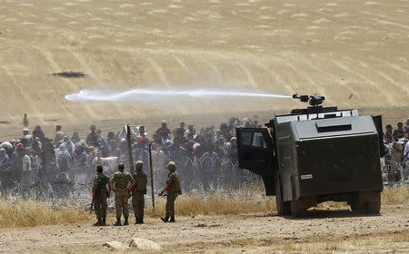 FILE PHOTO - Turkish military use water cannon to stop Syrian refugees as they wait behind the border fences to cross into Turkey on the Turkish-Syrian border, near the southeastern town of Akcakale in Sanliurfa province, Turkey, June 5, 2015. REUTERS/Osman Orsal/File Photo