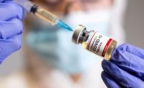 FILE PHOTO: A woman holds a medical syringe and a small bottle labeled "Coronavirus COVID-19 Vaccine\