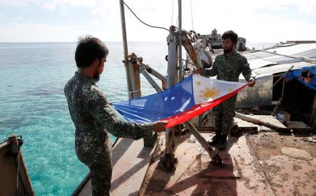 FILE PHOTO - Philippine Marines fold a Philippine national flag during a flag retreat at the BRP Sierra Madre, a marooned transport ship in the disputed Second Thomas Shoal, part of the Spratly Islands in the South China Sea, March 29, 2014. REUTERS/Erik De Castro/File Photo