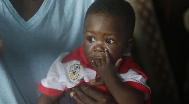 Nurse Donnell Tholley, 25, holds his adopted son Donnell Junior at their apartment in Freetown, Sierra Leone.