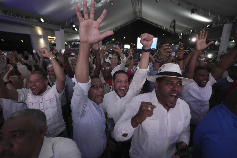 Los partidarios del actual candidato presidencial Luis Abinader reaccionan después de escuchar los resultados del primer recuento de votos durante las elecciones generales en Santo Domingo