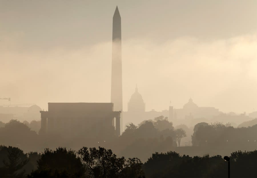 FILE- In this Sept. 26, 2014, photo, the monuments of Washington are silhouetted through the lifting fog over the nation’s capitol as seen from an overlook in Arlington, Va. From left are, the Lincoln Memorial, Washington Monument, the Capitol, the Smithsonian Castle, and the Library of Congress. Government surveyors have determined a new height for the Washington Monument that’s nearly 10 inches shorter than what has been thought for more than 130 years, officials will announce Monday, Feb. 16, 2015. (AP Photo/J. Scott Applewhite, File)