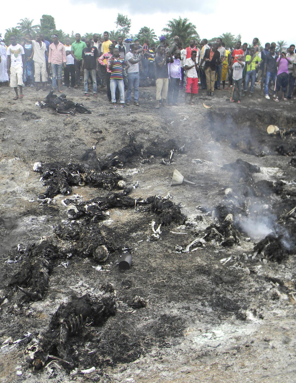 People look at charred bodies following fuel tanker explosion in Okogbe near Port Harcourt Nigeria, Thursday, July 12, 2012. A truck carrying fuel caught fire and exploded in Nigeria on Thursday after it veered off the road into a ditch, killing at least 95 people who had rushed to the scene to scoop fuel that had spilled, an official said.(AP Photo)