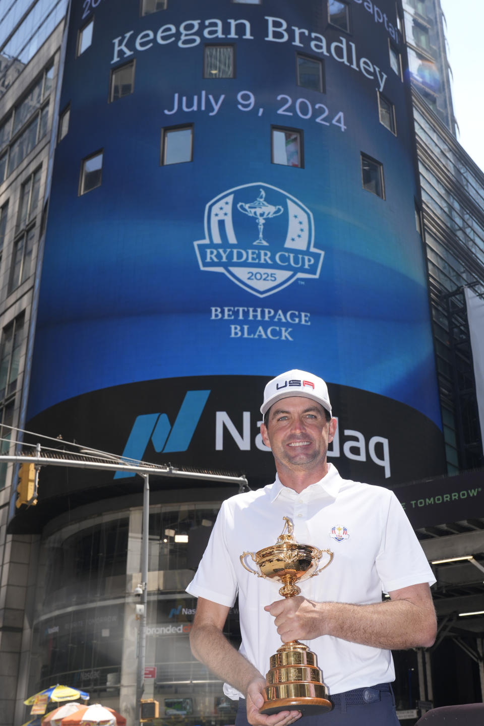 Keegan Bradley, holding a Ryder Cup trophy, poses in front of the NASDAQ building in New York, Tuesday, July 9, 2024. Bradley was introduced as the U.S. Ryder Cup captain for 2025. (AP Photo/Seth Wenig)