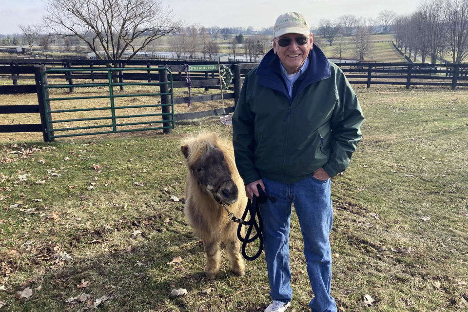 Michael Blowen leads his pet miniature horse, Little Silver Charm, on a walk Wednesday, Jan. 3, 2024, at Old Friends retirement horse farm at Georgetown, Ky. Little Silver Charm has been a fixture at the farm. Blowen announced Wednesday that he's stepping down as president of the thoroughbred retirement farm he founded. (AP Photo/Bruce Schreiner)