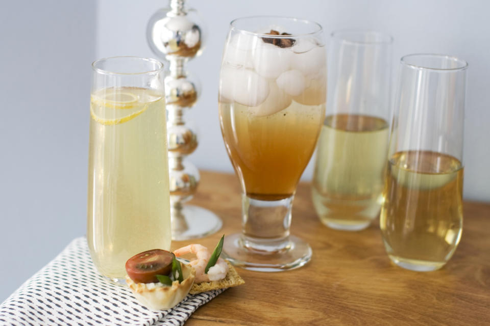 In this image taken on Jan. 28, 2013, from left, a glass of citrus bubbly with a small curl of lemon on top, a glass of spiced rose-pomegranate spritzer with a star anise on top, and two glasses of sparkling wine, with canapes are shown on a table in Concord, N.H. (AP Photo/Matthew Mead)