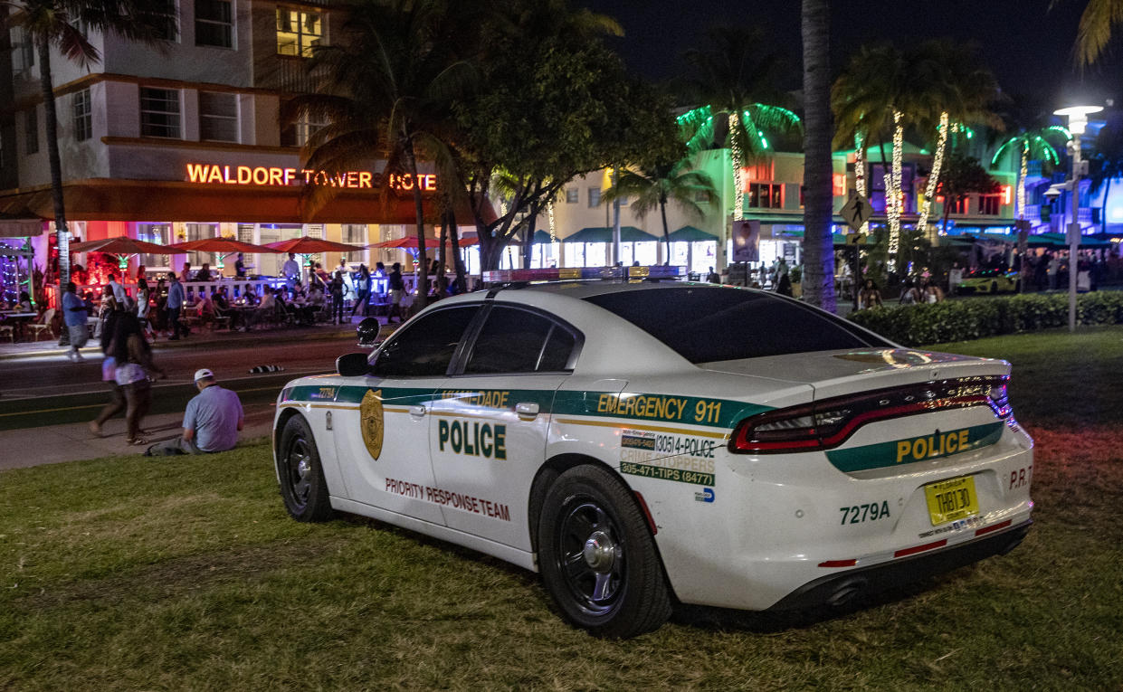 Miami-Dade Police Department personnel are seen on Ocean Drive Saturday night before the midnight curfew imposed by the City of Miami Beach, Fla., Saturday March 26, 2022. Miami Beach officials have spent recent years trying to control the raucous crowds, public drinking and growing violence associated with the city's world-famous South Beach neighborhood during spring break. (Pedro Portal/Miami Herald via AP)