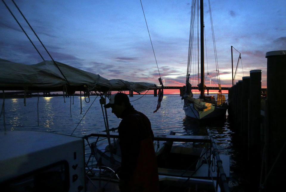 In this Dec. 20, 2013 picture, Capt. David Whitelock prepares for a day of oyster dredging on the skipjack Hilda M. Willing as the sun begins to rise over Deal Island, Md. Only after buying the 109-year-old vessel from another family of watermen did Whitelock discover that it once belonged to his great-great grandfather. (AP Photo/Patrick Semansky)