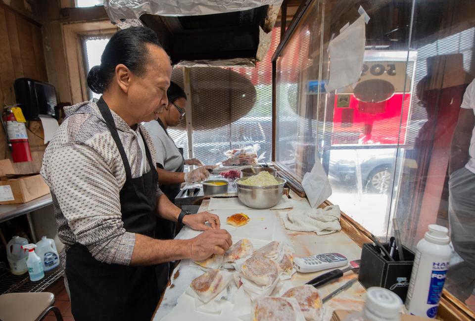 Big Apple Inn owner Geno Lee wraps sandwiches for a waiting customer Wednesday, March 16, 2022. Lee is the fourth generation to run the eight-decade-old Jackson, Miss., restaurant. As Lee wraps, employee Sharon Winters Taylor of Jackson, background, makes Smokes, sausage sandwiches, and Ears, pig ear sandwiches.