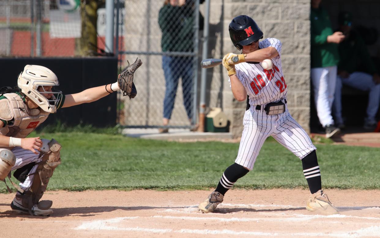 Kam Ackley takes a high pitch for Milan in front of St. Mary Catholic Central catcher Drew Bylow on Monday, April 22, 2024. SMCC won 13-2.