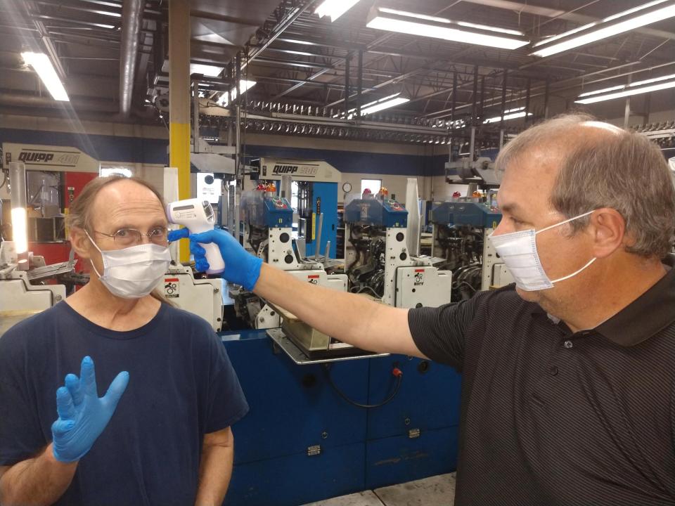 Record Searchlight Packaging Center Manager Brad Maplesden, right, takes the temperature of building maintenance tech Ron Weyrick on April 30, 2020, as part of the newspaper’s safety procedures during the global pandemic.