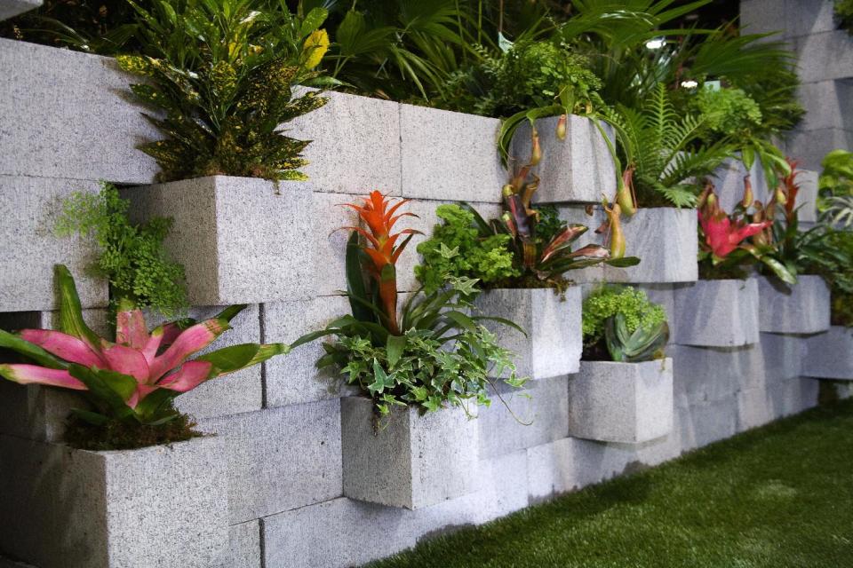 In this publicity photo provided by Chris H. Olsen, the Landscape Designer, Olsen, of Little Rock, Ark., created a decorative wall out of concrete blocks planted with ivy and tropical plants. Cement couches, benches and tables also can be made by stacking concrete blocks. “You don’t even have to mortar it,” he says. Olsen shares more outdoor decorating ideas in his book "Chris H. Olsen's Five Seasons" (Leisure Arts, 2011). (AP Photo/Chris H. Olsen, Janet Warlick/Camera Work)