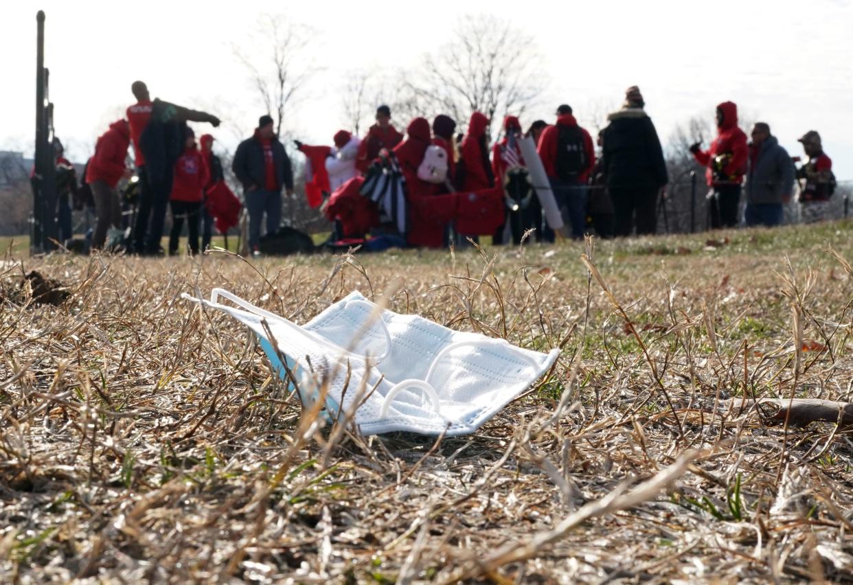 A discarded mask lies on the ground as demonstrators participate in a Defeat the Mandates march.