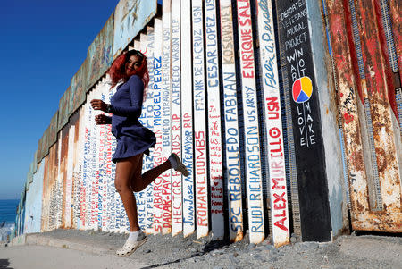 FILE PHOTO: Yaderin Alexandra Banias, a migrant from Honduras, part of a caravan of thousands traveling from Central America en route to the United States, poses in front of the border wall between the U.S. and Mexico in Tijuana, Mexico, November 23, 2018. REUTERS/Kim Kyung-Hoon