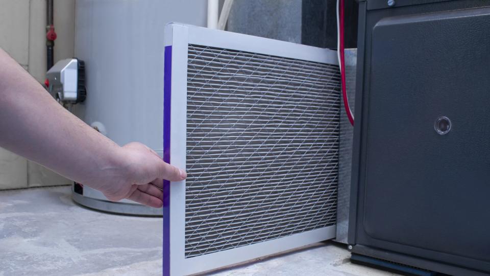a person changing an air filter on a high efficiency furnace